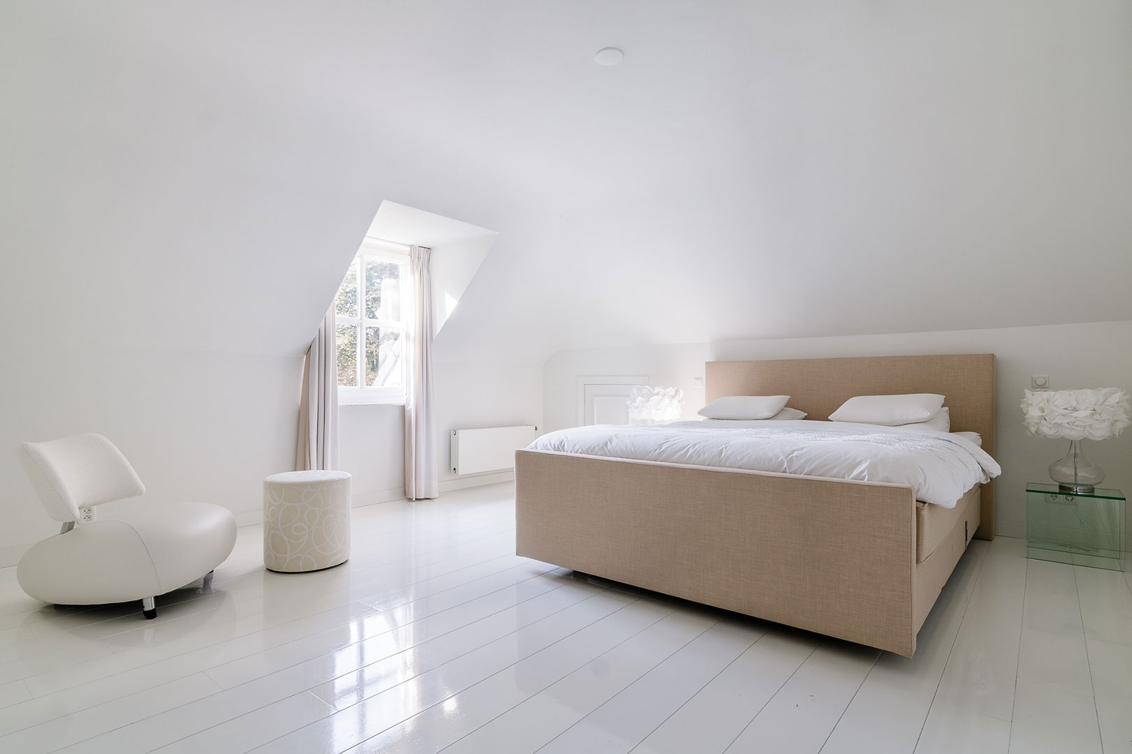 Rustige witte slaapkamer met een beige tweepersoonsbed